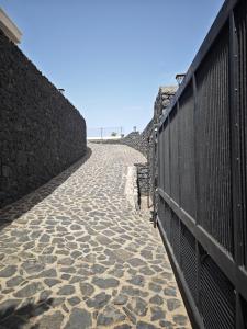 einen steinernen Gehweg neben einer Mauer mit einem Zaun in der Unterkunft Villa compartida Gonzalez in Radazul