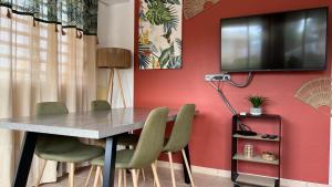 een eettafel met stoelen en een tv aan een rode muur bij F2 rénové, climatisé et lumineux in Cayenne