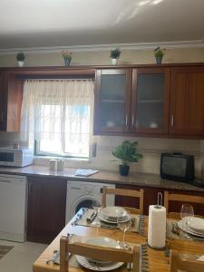 una cocina con armarios de madera y una mesa con platos. en Brisa Castro, en Nazaré