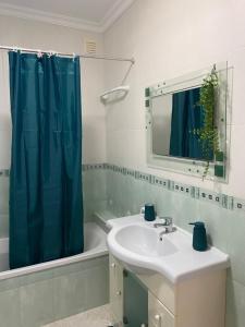 La salle de bains est pourvue d'un lavabo et d'un rideau de douche bleu. dans l'établissement Brisa Castro, à Nazaré