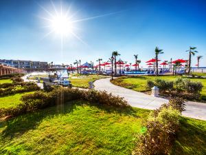 a view of a park with palm trees and the sun at Porto Matrouh Beach Resort in Marsa Matruh