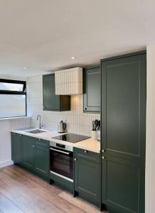 a kitchen with green cabinets and a sink at Chic Barn Conversion in the Cotwolds in Enstone
