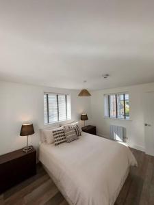 a bedroom with a white bed and two windows at Chic Barn Conversion in the Cotwolds in Enstone