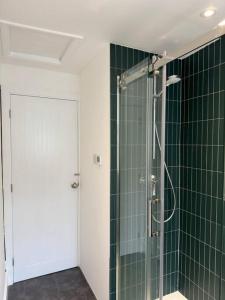 a bathroom with a shower with green tiled walls at Chic Barn Conversion in the Cotwolds in Enstone
