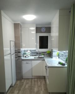 a white kitchen with a sink and a refrigerator at SOL & MAR Playa de las vistas Torres del Sol A504 in Arona