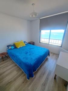1 dormitorio con 1 cama con edredón azul y 2 ventanas en DEPARTAMENTO FRENTE AL MAR, en Iquique