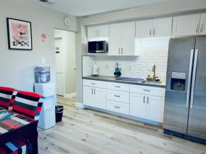 a kitchen with white cabinets and a stainless steel refrigerator at Brand new suite, 1mi to Meta, 3mi to Stanford in East Palo Alto