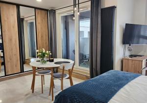 een slaapkamer met een bed en een tafel en stoelen bij URBAN APARTMENTS PREMIUM Baildona 18A with GARAGE in Katowice
