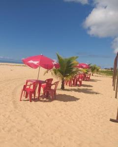 una fila de sillas y sombrillas rojas en una playa en Casa de Praia do Marcinho en Prado