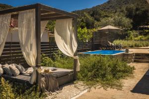 a pergola with a bed next to a pool at Berthina House in Dhrakopouláta