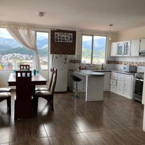 eine Küche mit weißen Schränken und einem Tisch und Stühlen in der Unterkunft Departamento acogedor y moderno, vista increíble. in Loja