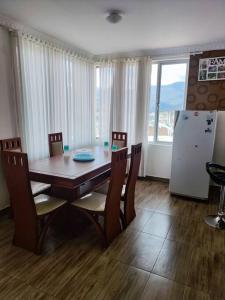 comedor con mesa, sillas y nevera en Departamento acogedor y moderno, vista increíble., en Loja