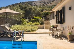 a pool with chairs and an umbrella next to a house at Berthina House in Dhrakopouláta