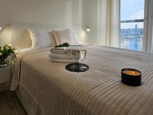 a bed with two wine glasses and a candle on it at URBAN APARTMENTS LUXURY SKYLINE Sokolska Towers 30A City Center, 2 garages, gym and sauna, IMPREZY ZAKAZANE PARTIES PROHIBITED in Katowice