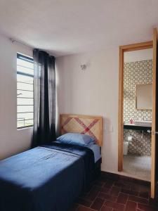 1 dormitorio con cama, ventana y espejo en Casa Nabani Oaxaca, en Oaxaca City