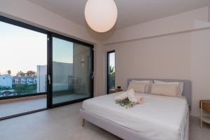 a bedroom with a white bed and large windows at SithoniaRS Luxury Three Floors Villa With Private Pool & Garden in Nikiti +99 photos