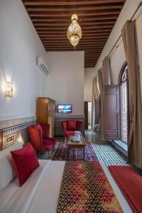 a hotel room with a bed and red chairs at Riad Fes Ziyat & Spa in Fès