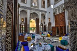 a restaurant with tables and chairs in a building at Riad Fes Ziyat & Spa in Fez