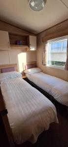 two beds in a small room with a window at NB166 - Porth Bay Hideaway in Porth