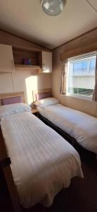 two beds in a small room with a window at NB166 - Porth Bay Hideaway in Newquay Bay Resort +6 photos