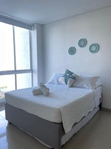 Un dormitorio blanco con una cama grande con toallas. en Reserva Del Mar, en Santa Marta