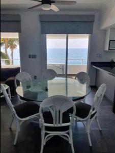 een eetkamer met een glazen tafel en stoelen bij DPTO. A orilla del Mar in Manzanillo
