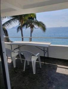 een tafel en stoelen op een balkon met uitzicht op de oceaan bij DPTO. A orilla del Mar in Manzanillo