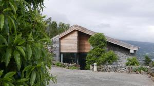 a stone and wood house with a tree at Lava Homes in Santo Amaro
