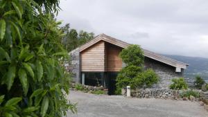 una casa de piedra y madera con un árbol en Lava Homes, en Santo Amaro