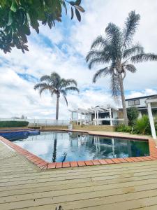 una piscina con palmeras y una casa en Fiji Vibe 4 Bedroom Oasis in Rototuna North en Hamilton