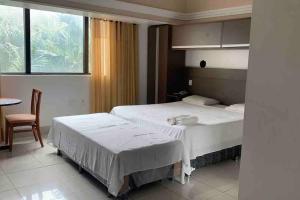 a bedroom with two beds and a table and a window at Flat em Tropical Executive Hotel in Manaus
