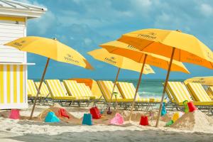 a group of yellow umbrellas and chairs on a beach at Hilton Cabana Miami Beach Resort in Miami Beach