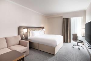 a hotel room with a large bed and a chair at Hilton London Gatwick Airport in Horley