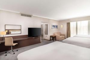 a hotel room with a bed and a desk with a television at Hilton London Gatwick Airport in Horley