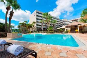 een zwembad in een resort met palmbomen en een gebouw bij DoubleTree Suites by Hilton Orlando at Disney Springs in Orlando