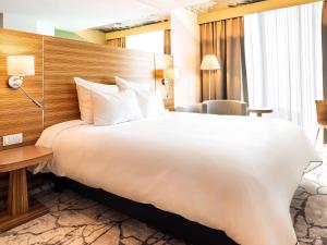 uma grande cama branca num quarto de hotel em Mercure Tallinn em Talin