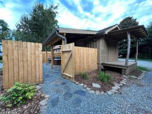 un cobertizo de madera con un banco y una valla en Blissful Nook Tiny Home ~ Cozy Retreat w/ Hot Tub; near Town and Deep Creek, en Bryson City