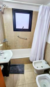 Un baño con bañera, inodoro y ventana. en Belgrano 555, en San Martín de los Andes