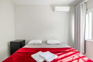 una camera da letto con un letto rosso con due asciugamani sopra di Casa 215 Suítes pertinho da Praia a Balneário Camboriú