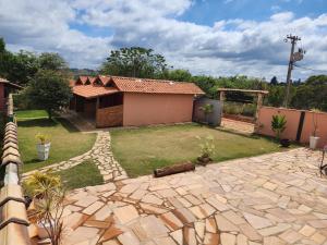 einen Hinterhof mit einem Haus und einer Steinterrasse in der Unterkunft Chalés Recanto dos Pássaros in São Thomé das Letras