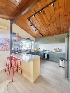 una cocina con una isla grande con 2 taburetes rojos en Fiji Vibe 4 Bedroom Oasis in Rototuna North, en Hamilton