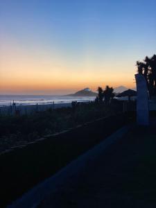 a sunset over the ocean with a mountain in the distance at Casa do Point in Saquarema