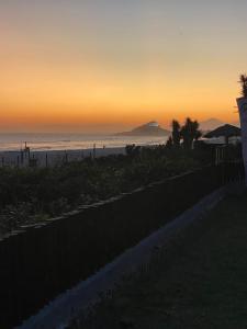 um pôr-do-sol sobre uma praia com uma cerca e o oceano em Casa do Point em Saquarema