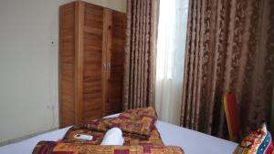 a room with a bed with a table and a cabinet at Crystal Premier Hotel in Pantang