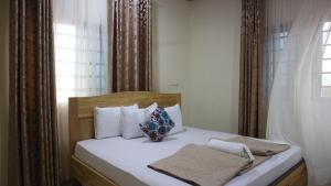 una camera da letto con un letto con cuscini bianchi e una finestra di Crystal Premier Hotel a Pantang