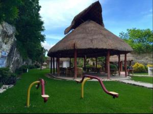 a gazebo with a roof and two slides in the grass at Cozy Apartments in Puerto Morelos in Puerto Morelos