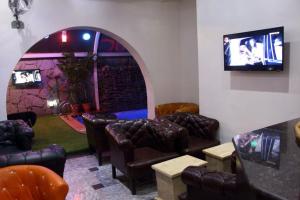 uma sala de espera com cadeiras de couro e uma televisão em E-Suites Hotel, Abuja em Abuja