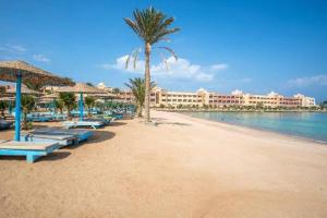 a beach with chairs and a palm tree and a hotel at Zahabia beach and resort in Hurghada
