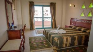 a bedroom with a bed and a table and a window at Zahabia beach and resort in Hurghada