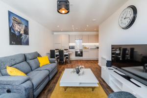 a living room with a couch and a clock on the wall at Contemporary 2 bedroom Apartment - Birmingham City Centre - Digbeth Bullring in Birmingham